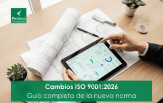 Mesa de trabajo estratégica con las manos de un profesional señalando una tablet con gráficos, junto a un plano técnico, simbolizando los cambios de la ISO 9001:2026 hacia la digitalización